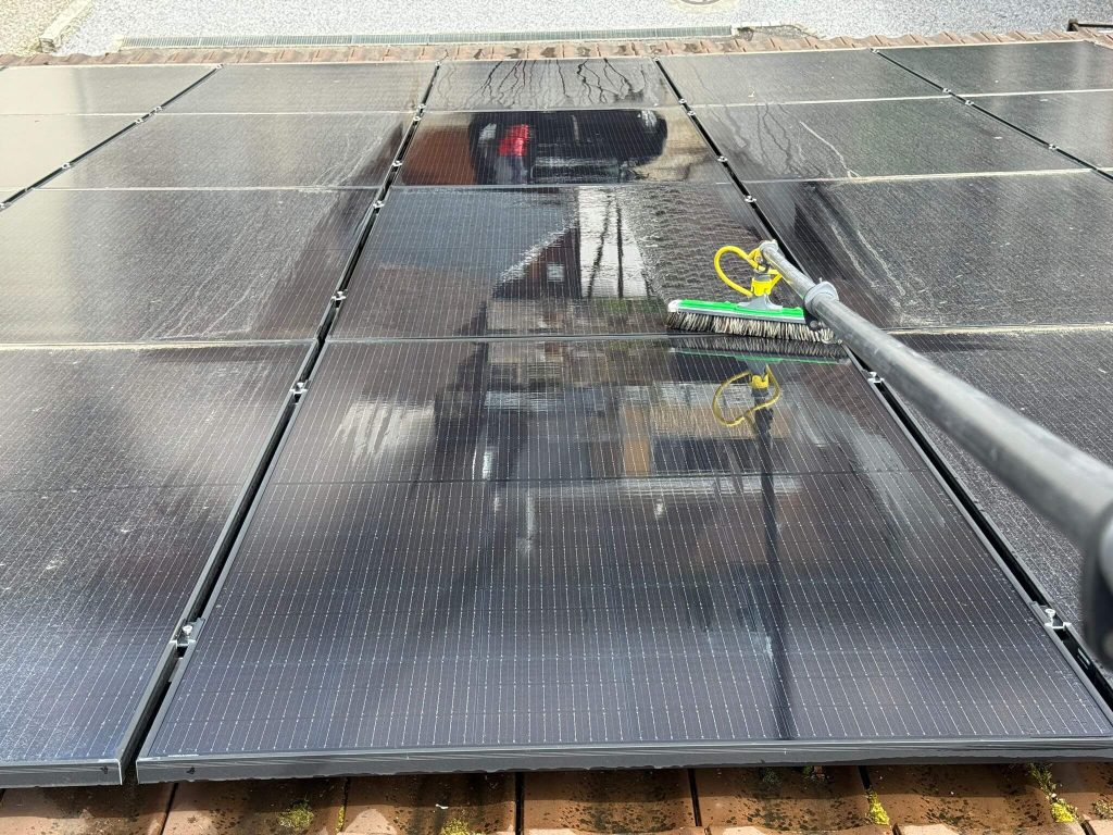 Fachkraft von Swissprofi Reinigungen reinigt Solarpanels auf einem Steildach mit reinem Osmosewasser.